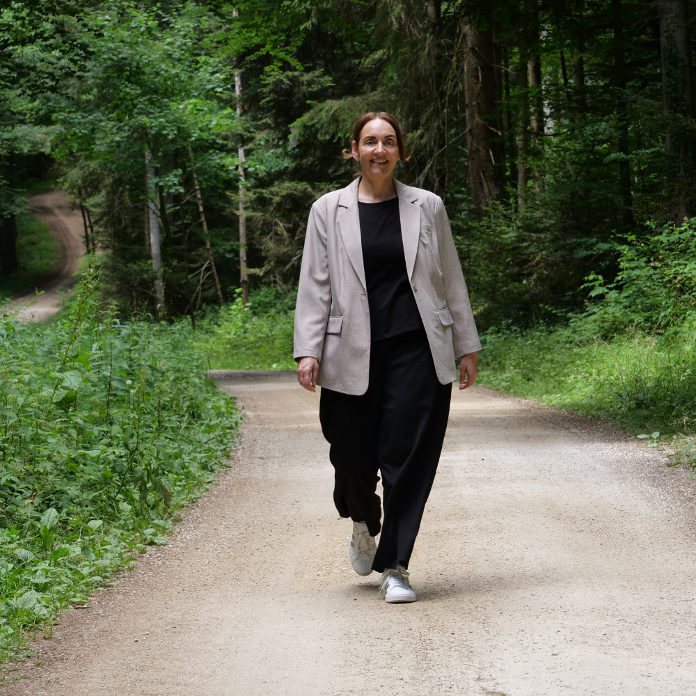 Frau steht im Wald und lächelt in die Kamera